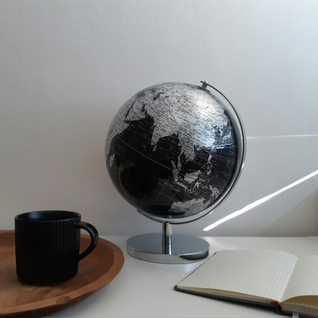 pexels photo 10160241 10160241 Aesthetic workspace with a globe, ceramic mug, and notebook on a white background.
